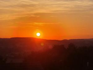 a sunset with the sun setting on a hill at Ferienwohnung Familie Kleinbauer in Wirsberg