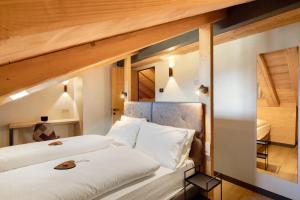 Dos camas en una habitación con techos de madera. en Rain Villa Genf Spa - Relax, en Livigno