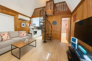 ein Wohnzimmer mit einem Sofa und einer Wendeltreppe in der Unterkunft Cottage-pvt Lake & Pool Access Near Disney Wporch in Castle Hill