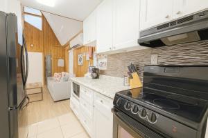 eine Küche mit weißen Schränken und einem schwarzen Herd mit Backofen in der Unterkunft Cottage-pvt Lake & Pool Access Near Disney Wporch in Castle Hill