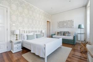 a white bedroom with a bed and a couch at GuestReady - Charming House Marquês in Porto