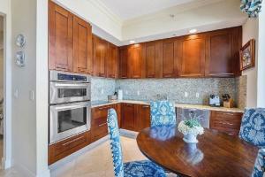 a kitchen with wooden cabinets and a wooden table at Elegant 2 Bedroom Condo with Ocean Views in West Palm Beach