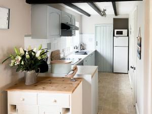 a kitchen with white cabinets and a vase of flowers on a counter at The Old Barn-E1425 in Winthorpe