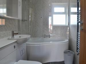 a white bathroom with a tub and a sink at Benlli in Aberdaron