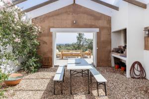eine Terrasse mit Tisch und Bänken in einem Gebäude in der Unterkunft Casa Acima in São Bartolomeu da Serra