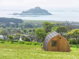 ein Holzschuppen auf einem Feld mit einer Insel in der Ferne in der Unterkunft Scenic Bay in Ludgvan