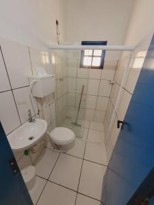 a white bathroom with a toilet and a sink at Chalé tangará praia do sono in Ponta Negra