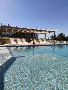 a swimming pool with white lounge chairs in the water at Cabañas La Catalana in Tandil