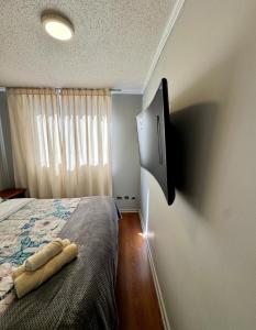 ein Schlafzimmer mit einem Bett und einem Fernseher an der Wand in der Unterkunft Departamento Teatinos Santiago Centro in Santiago