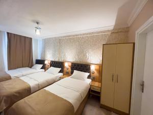 a hotel room with three beds and a cabinet at Helen Inn in İzmir