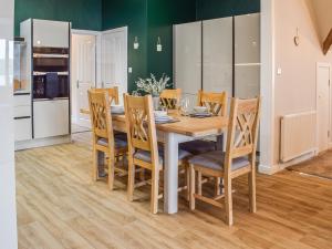 a kitchen and dining room with a wooden table and chairs at Gleaner Lea Apartment in Campbeltown