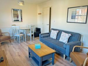 a living room with a blue couch and a table at Solara Breeze in Reighton
