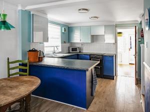 a kitchen with blue cabinets and a wooden table at Painter's Cottage in Hemsby
