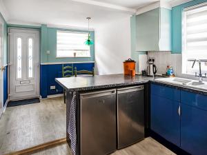 a kitchen with blue cabinets and a counter top at Painter's Cottage in Hemsby