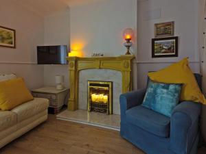 a living room with a fireplace with a couch and a chair at Painter's Cottage in Hemsby