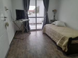 a bedroom with a bed and a television on a tiled floor at Piscis in San Nicolás de los Arroyos