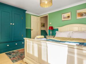 a bedroom with green walls and a white bed at Painter's Cottage in Hemsby +12 photos