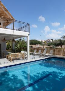 a large swimming pool with chairs and a deck at Ella Sun - Coconut Villa in Eilat