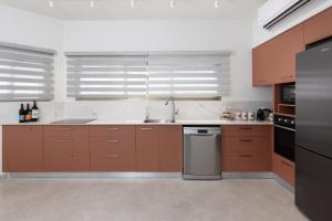 a kitchen with brown cabinets and a stainless steel dishwasher at Ella Sun - Coconut Villa in Eilat