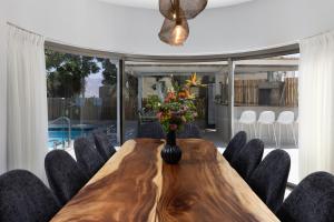 a dining room table with chairs and a vase with flowers at Ella Sun - Coconut Villa in Eilat +90 photos