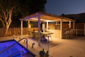 a patio with a table and a swimming pool at night at Ella Sun - Coconut Villa in Eilat
