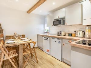 Una cocina con gabinetes blancos y una mesa de madera. en The Hayloft-Uk34015, en Godshill