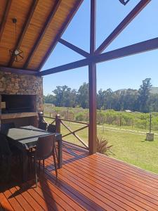 a screened in porch with a table and a fireplace at Cabañas La Catalana in Tandil