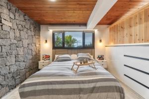 een slaapkamer met een groot bed en een stenen muur bij Vista Teide in Tacoronte +20 foto's