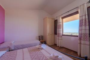 アリエントゥにあるCasa Ginepro piscina e vista mareのベッドが2つと大きな窓がある寝室