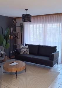 a living room with a black couch and a table at Altrove Leukerbad - Modern & Central in Leukerbad