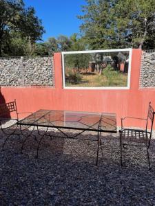 two chairs and a glass table in front of a wall at Gîte - Les Salons du Bastier in Ginasservis