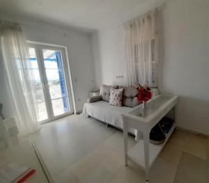 a white living room with a couch and a window at Haus Asterakia in Aliko Beach