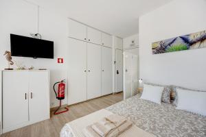 a white bedroom with a bed and a flat screen tv at Casa da Torralta in Alvor