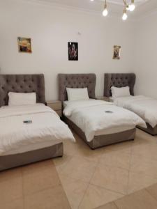 two beds in a room with white walls at شقة عائلية مودرن 4 غرف نوم رقم 1 in Quai