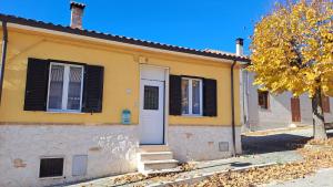 une petite maison jaune avec une porte blanche dans l'établissement Casa Albe, à Massa dʼAlbe