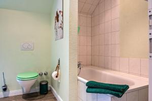 Un baño con inodoro verde y bañera. en Ferienwohnung Flut am Weserstrand, en Sandstedt 18 fotos más