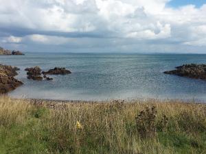 a large body of water with rocks and grass at Home Farm in Dunragit