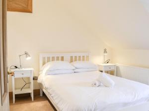 DunragitHome Farm的一间卧室配有两张带白色床单和两盏灯的床。