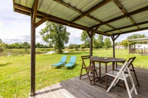 a wooden deck with chairs and a table and chairs at L'héberge du lac d'Isachris mh6 in Queyrac +4 photos