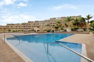 a swimming pool in front of a large building at La Perla D14 By Médano Rentals in El Médano