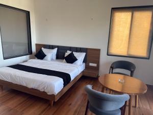 a bedroom with a bed and a table and a window at kanchan kutir villa in Jāmb