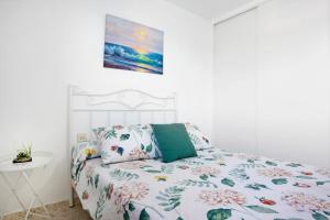 Un dormitorio blanco con una cama con un edredón floral. en Apartamento Almar, en Poblado de Sancti Petri