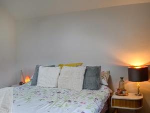 ein Schlafzimmer mit einem Bett und einem Tisch mit einer Lampe in der Unterkunft The Old Dairy Cottage Ainstable in Ainstable