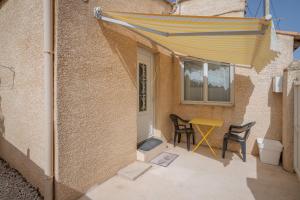 eine Terrasse mit einem Tisch und einem gelben Sonnenschirm in der Unterkunft Maison de pecheur la rose des vents in Valras-Plage