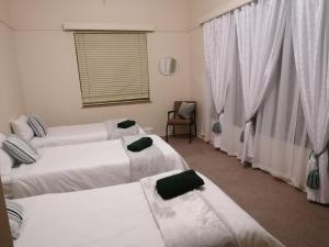 a room with three beds and a chair and a window at Agape Gastehuis in Jagersfontein