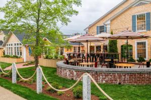 エドガータウンにあるEdgar Hotel Martha's Vineyard, an Ascend Collection Hotelのテーブルと椅子とパラソルのあるパティオ
