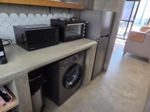 a kitchen with a microwave and a washing machine at Luvlé Lux Apartments in Eros Airport