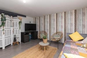a living room with a couch and chairs and a tv at Appartement Neuf Entre Lac et Océan in Léon