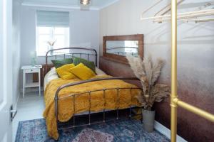 a bedroom with a bed with a yellow blanket and a mirror at Avalon Sunrise our enchanting Glastonbury cottage in Glastonbury