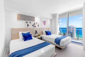two beds in a room with a view of the ocean at Luxury 2BR Apt With Ocean View Pool & Amenities in Hollywood Beach